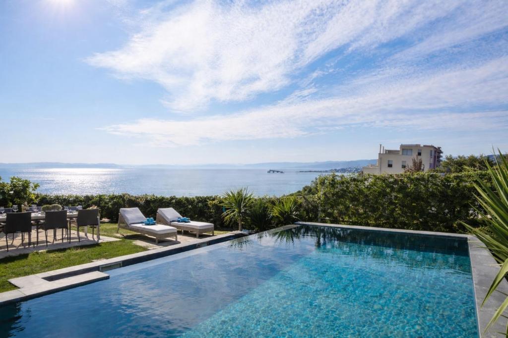 a swimming pool with a view of the ocean at Enjoyer - Seafront apartment with PRIVATE Heated POOL and terrace in Split