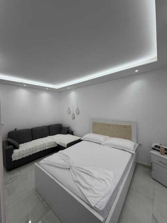 a white bedroom with a bed and a couch at Peaceful House in Përmet