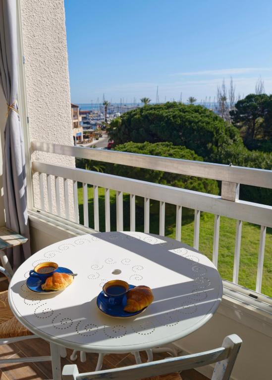a table with cups and croissants on a balcony at Vacances au port in Saint-Cyprien-Plage