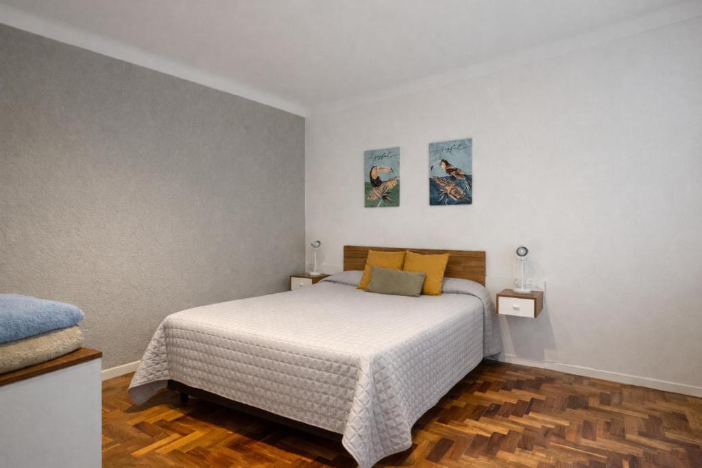 a bedroom with a bed with white sheets and yellow pillows at Ana Rent Departamento Moderno, Equipado full ,en San Isidro punto medio Tigre River y Tecnopolis in Boulogne