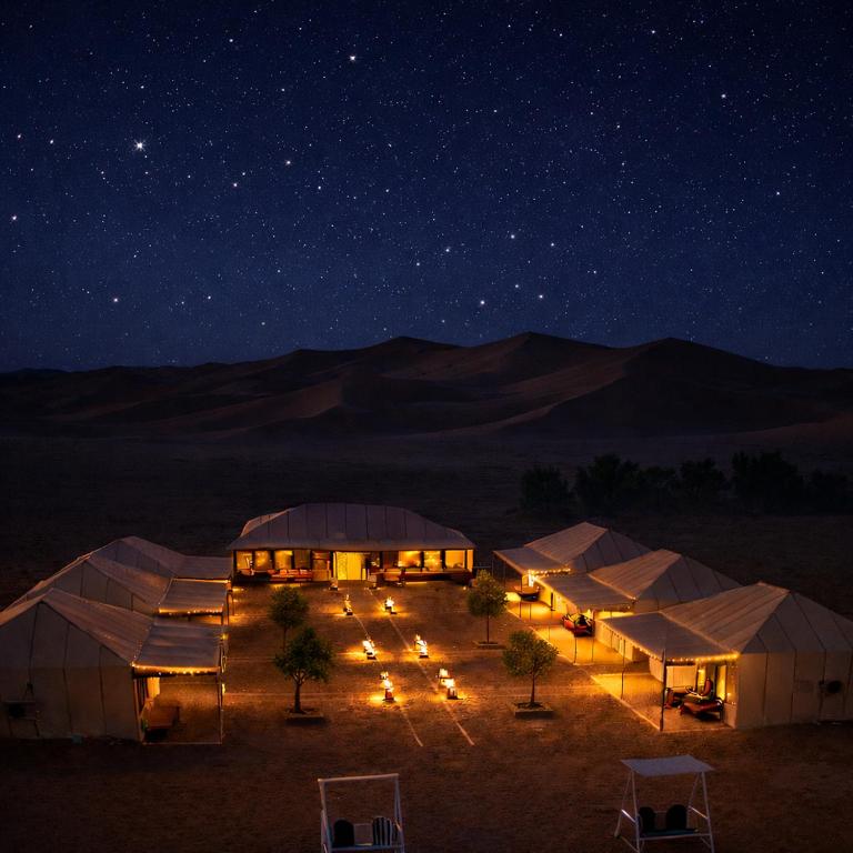 a group of tents in the desert at night at Achabou Desert Camp in Merzouga
