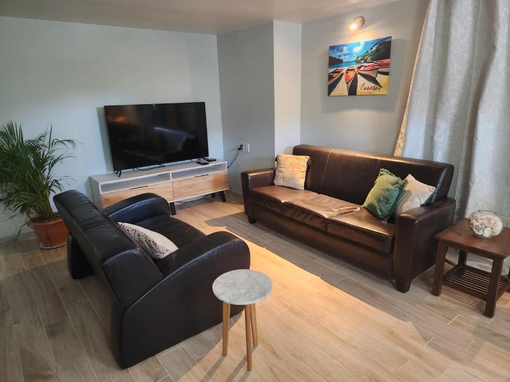 a living room with two couches and a flat screen tv at Kelly's Vacation Nest to Relax and Reactivate in Willemstad