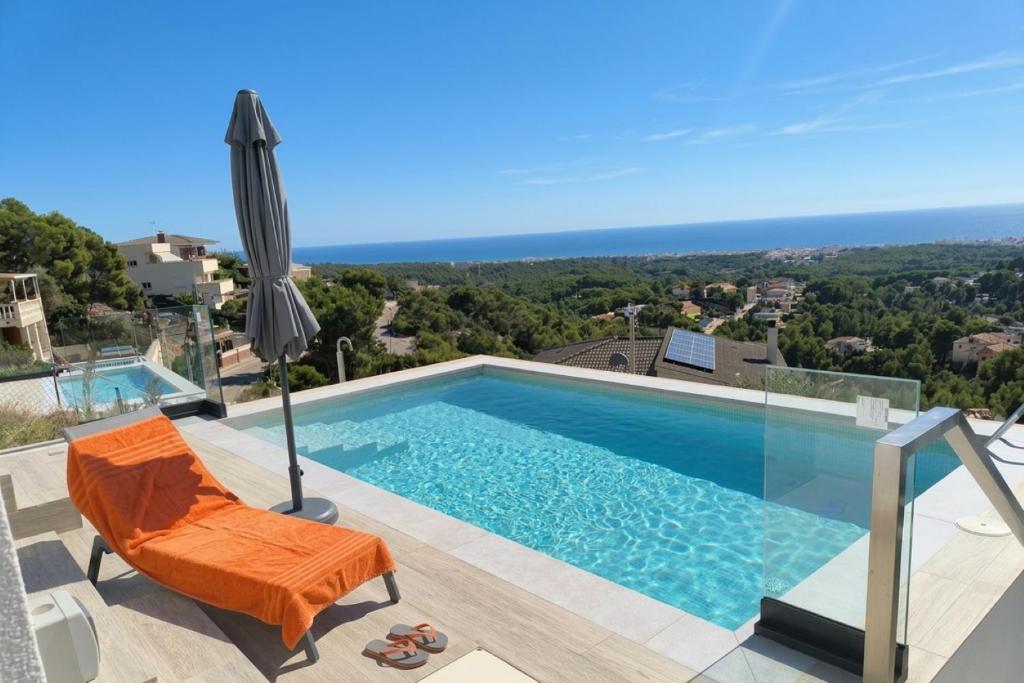 a swimming pool with an orange chair and an umbrella at Les Flors de Cunit Villa Edelweiss in Cunit