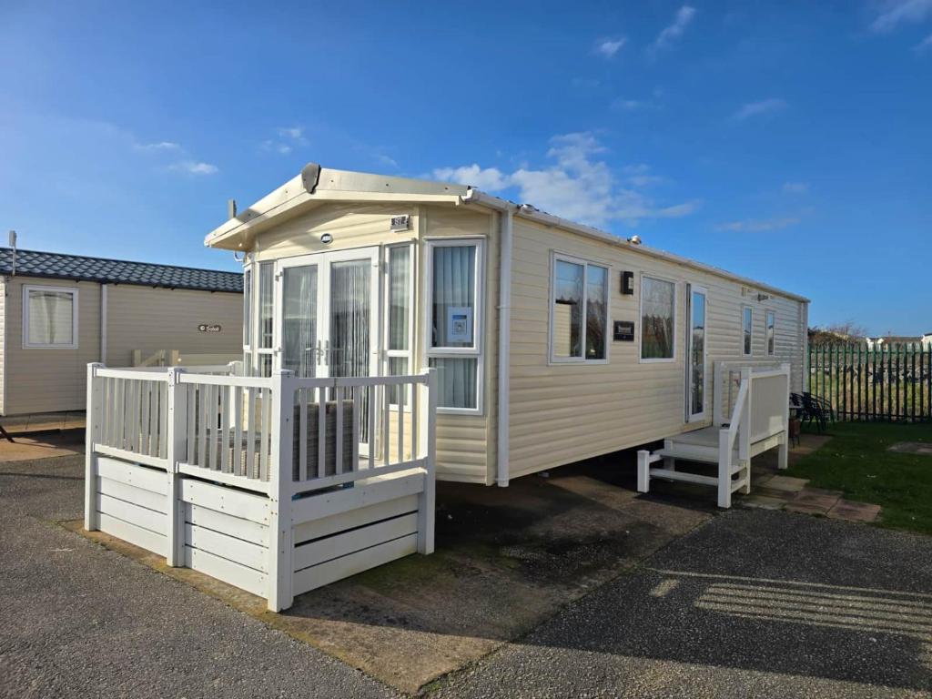 a tiny house parked in a lot with a porch at Towyn Happy Days S7 in Rowen