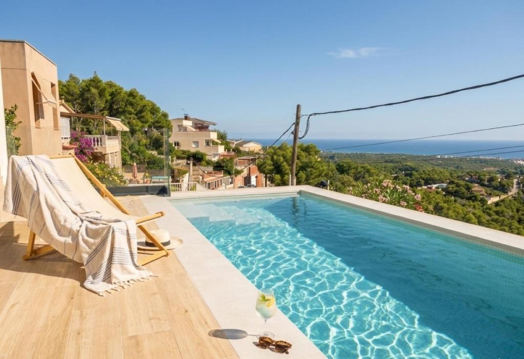 a swimming pool with a chair next to a house at Les Flors de Cunit Villa Liria in Cunit