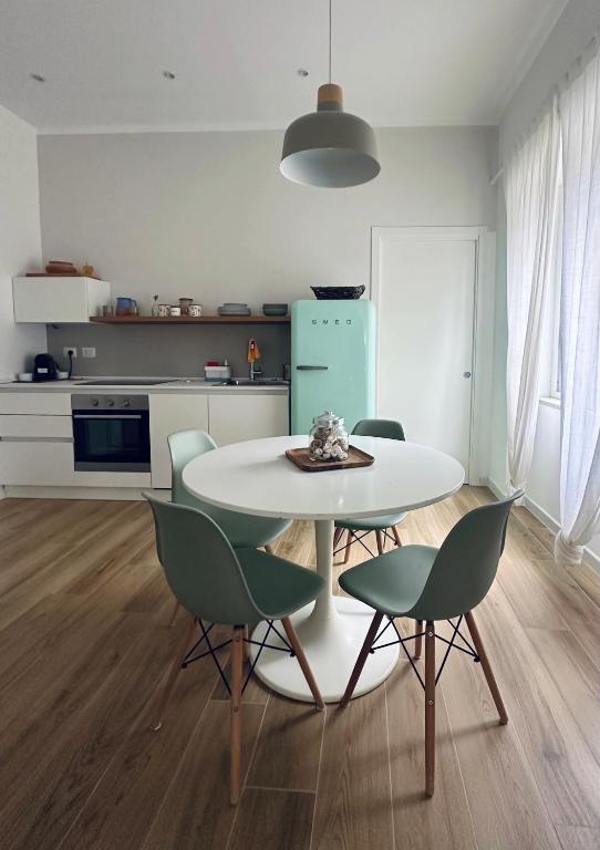 a kitchen with a white table and green chairs at Blu Bolivar in Marina di Camerota