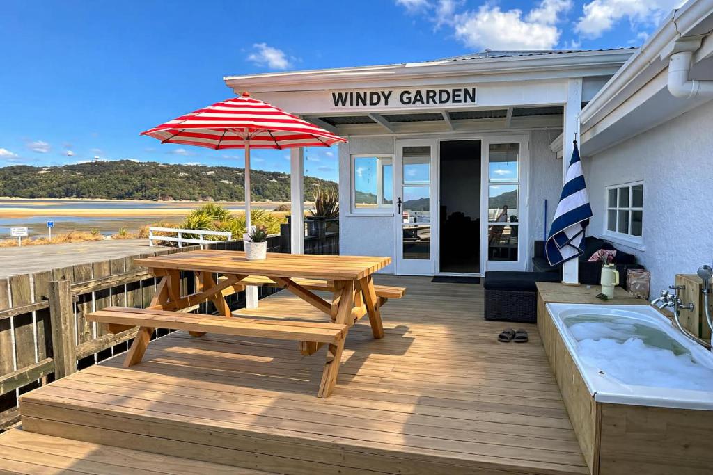 a wooden deck with a picnic table and an umbrella at Windy Garden in Marahau