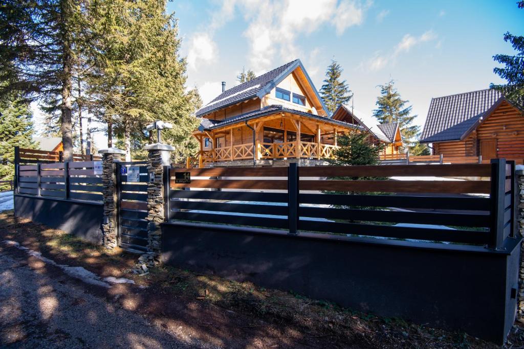 a wooden house with a fence in front of it at Vila Planinski Vuk Zlatar Nova Varoš in Vukovina