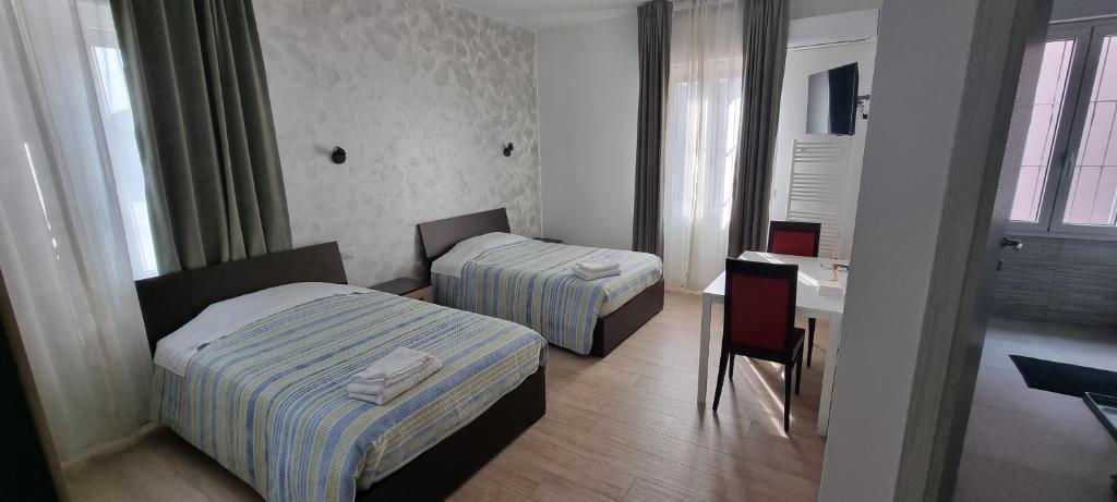 a hotel room with two beds and a table and a desk at La Locanda del Giardino in Lentate sul Seveso