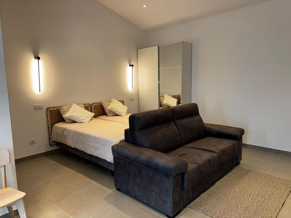 a bedroom with a bed and a couch and a chair at Casinha do Areeiro in Loulé