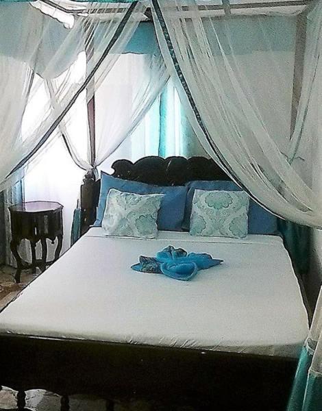 a bedroom with a bed with a canopy with blue clothes on it at Manch Lodge Vuga Zanzibar in Zanzibar City