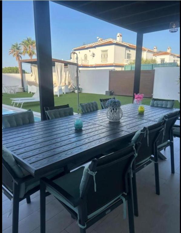 a wooden table and chairs on a patio at Chalet con 3 habitaciones Luz De Doñana in Mazagón