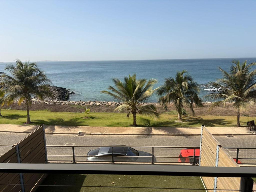 a car on a road with palm trees and the ocean at Studio B Luxury - Waterfront in Dakar