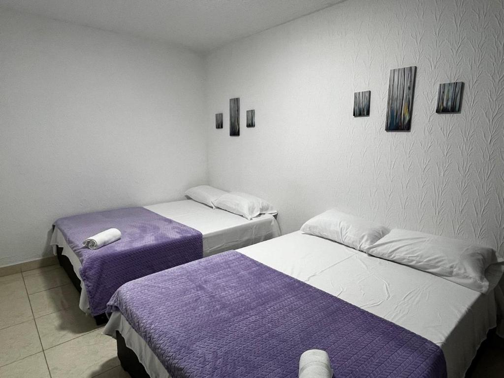 two beds in a room with purple and white at Apartamento Albergue - Buga in Buga
