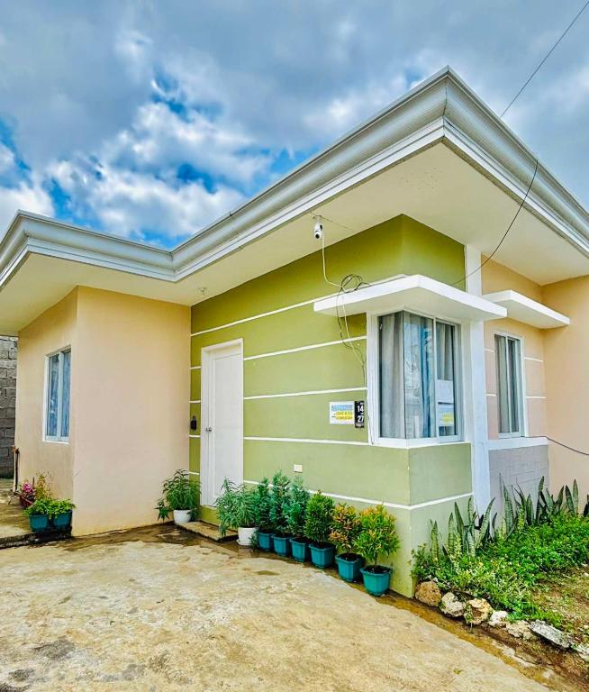 a yellow house with potted plants in front of it at LoveCo Vacation house close to Dahilayan with private parking in Manolo Fortich