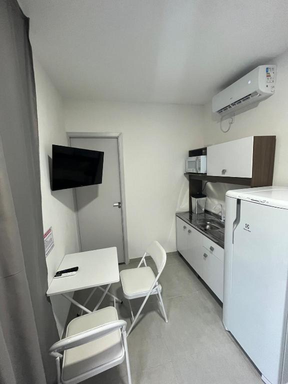 a small kitchen with a refrigerator and a table and chairs at Flat Container 3 Km do Centro de Brusque para até 4 pessoas in Brusque