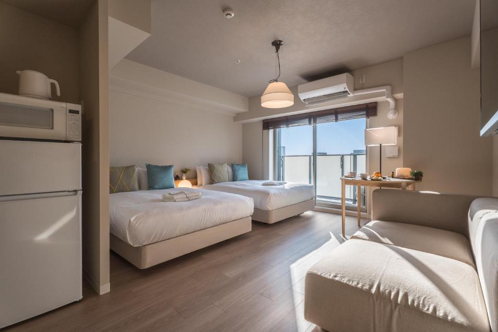 a bedroom with two beds and a living room with a couch at ESLEAD HOTEL Namba East in Osaka