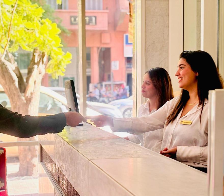 two women standing at a counter looking out of a window at La Renaissance hôtel Marrakech in Marrakesh
