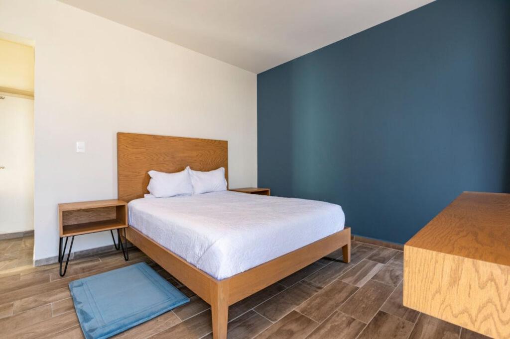 a bedroom with a bed and a blue wall at Hotel Kéri Inn in Guadalajara