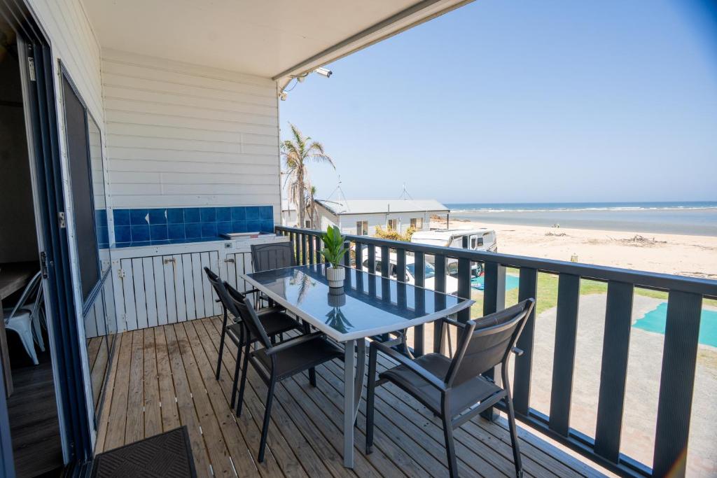 a table and chairs on a balcony with the beach at Tuross Beach Cabins & Campsites in Tuross Heads