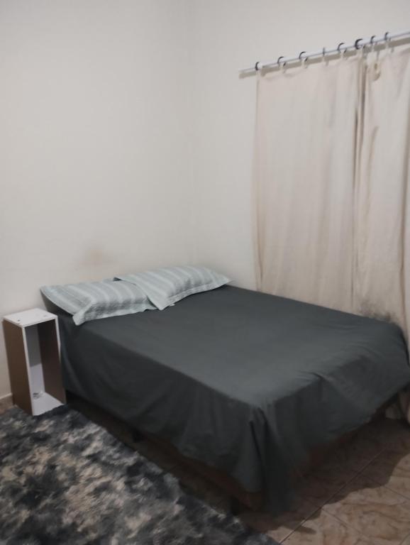 a bedroom with a bed with a curtain and a table at Quarto casal com banheiro in Sao Jose do Rio Preto