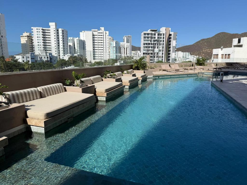 a swimming pool with lounge chairs and a city skyline at Exclusive Rodadero Sur Studio Apartment in Santa Marta