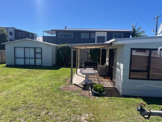 a backyard of a house with a table and a patio at Hosts on the Coast Ocean Corner in Whangamata