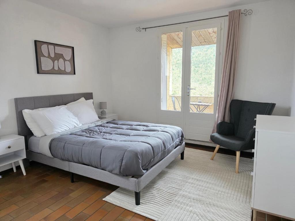 a bedroom with a bed and a chair and a window at Hostel du Canyon in La Palud-sur-Verdon