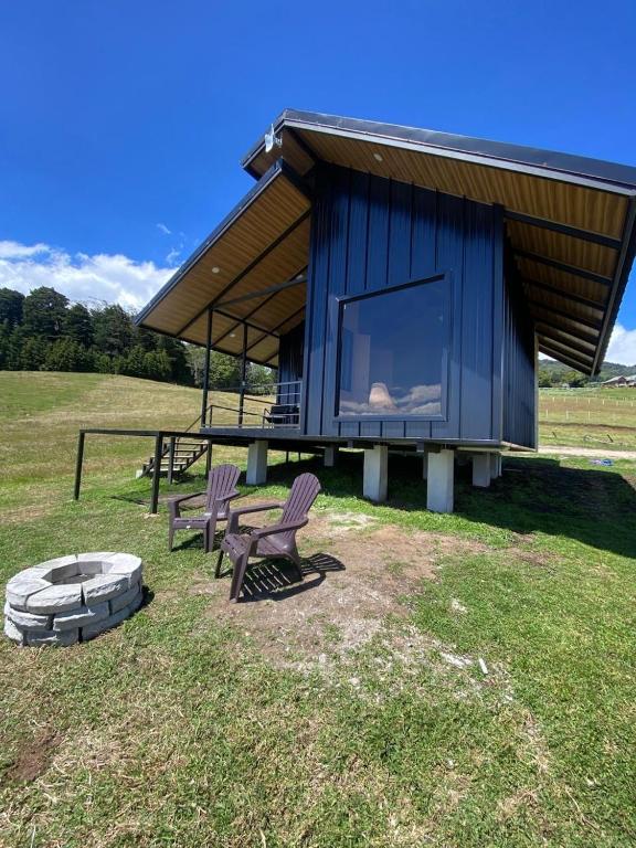 a blue building with two chairs and a fire pit at Cabaña Vistas de Lujo in Fraijanes