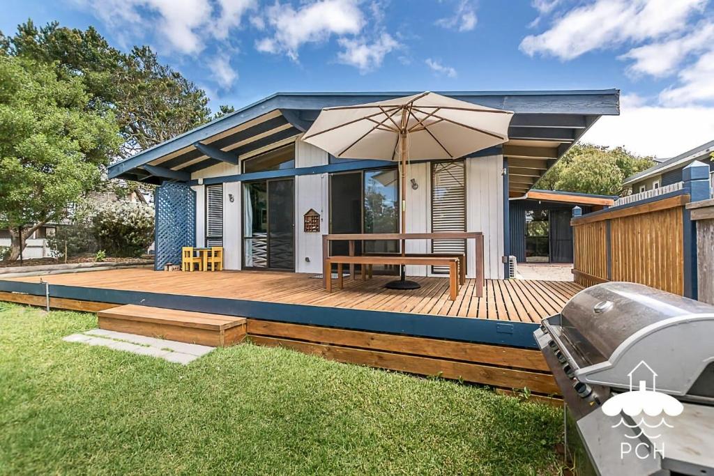 a house with a wooden deck with an umbrella at Dune Cottage Stay 3 Pay 2 Winter Special in Sandy Point