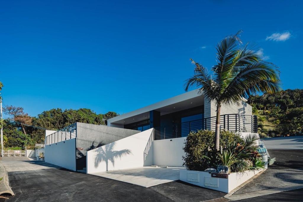 a house with a palm tree in front of it at Luxury Villa Maeda Unit2 in Onna
