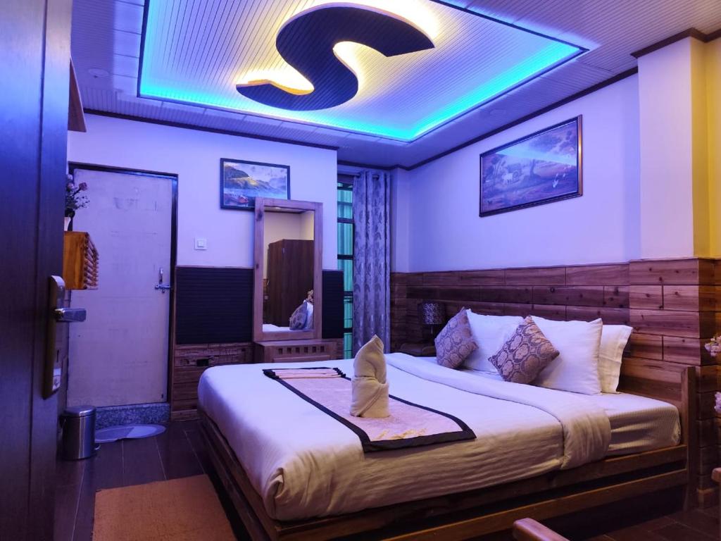 a bedroom with a large bed with a blue ceiling at Pradhan Hotel Mirik Lake Side in Mirik