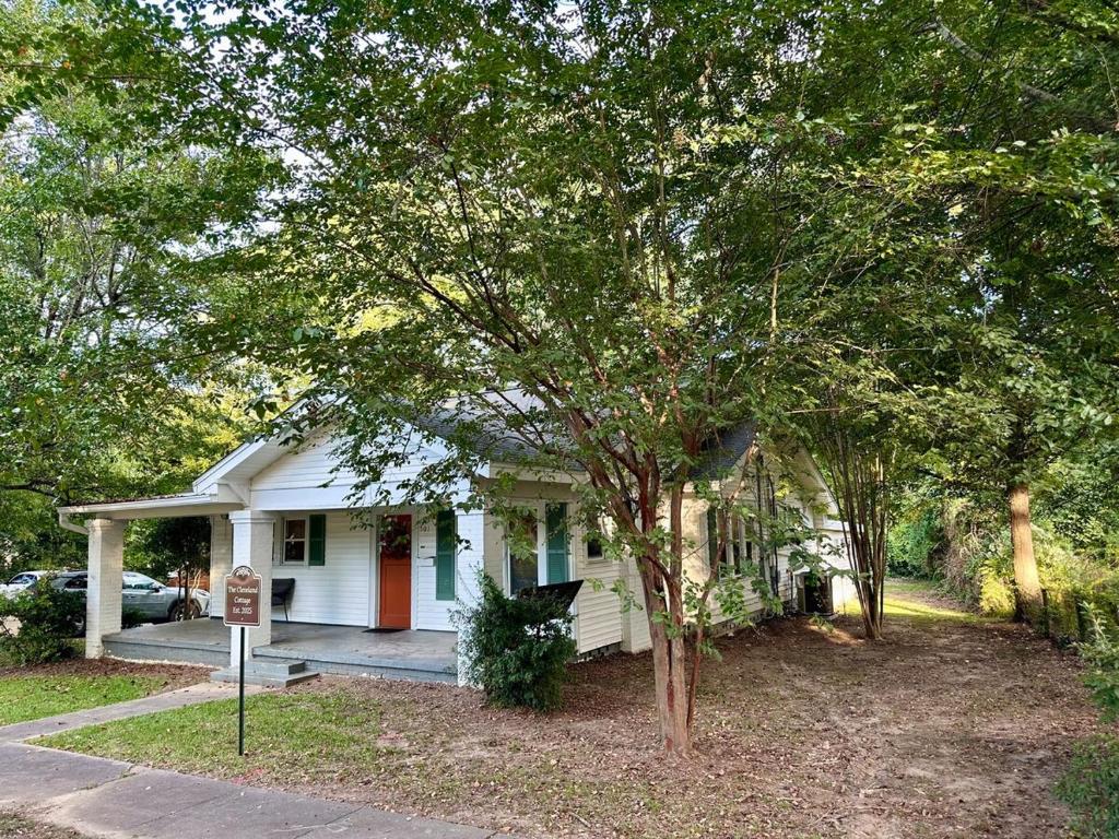 a white house with a tree in front of it at The Cleveland Cottage in Brookhaven