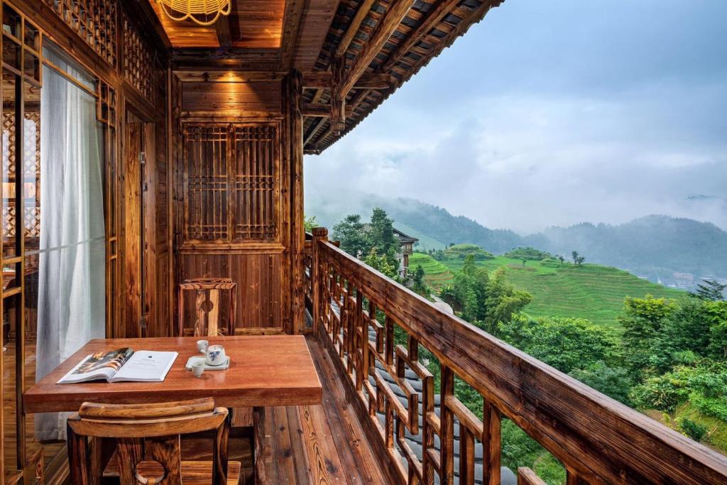 a balcony with a table and a view of a mountain at 素隐乡宿Hometown Destination红瑶吊脚楼 观景民宿 in Heping