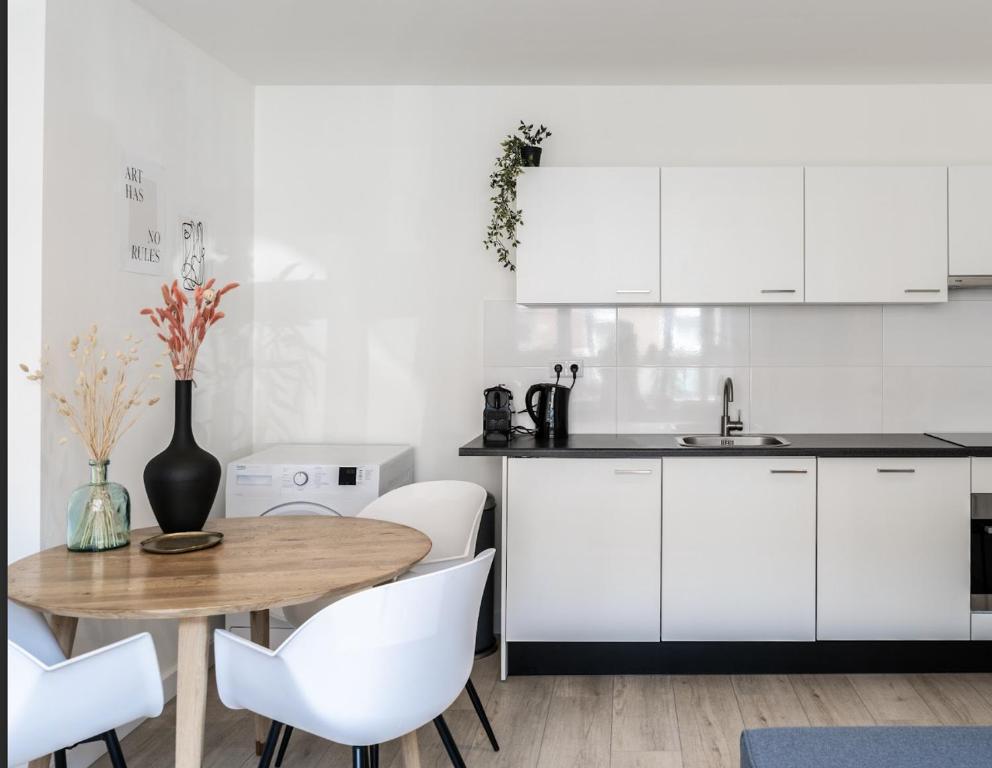 a kitchen with a wooden table and white cabinets at Spacious Family Stay Eindhoven, Garden & Kitchen in Eindhoven