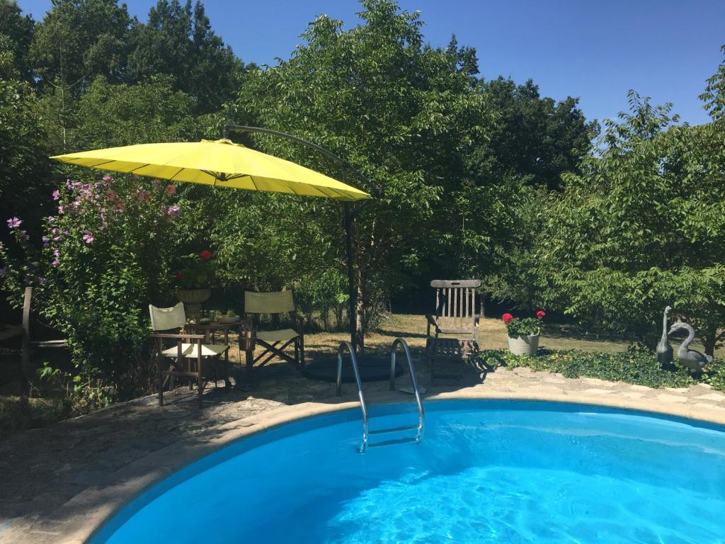 - une piscine avec un parasol jaune, une table et des chaises dans l'établissement Le Peyrail, à Les Lèves-et-Thoumeyragues