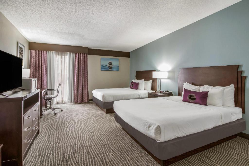 a hotel room with two beds and a flat screen tv at Clarion Hotel Jackson Northwest in Jackson
