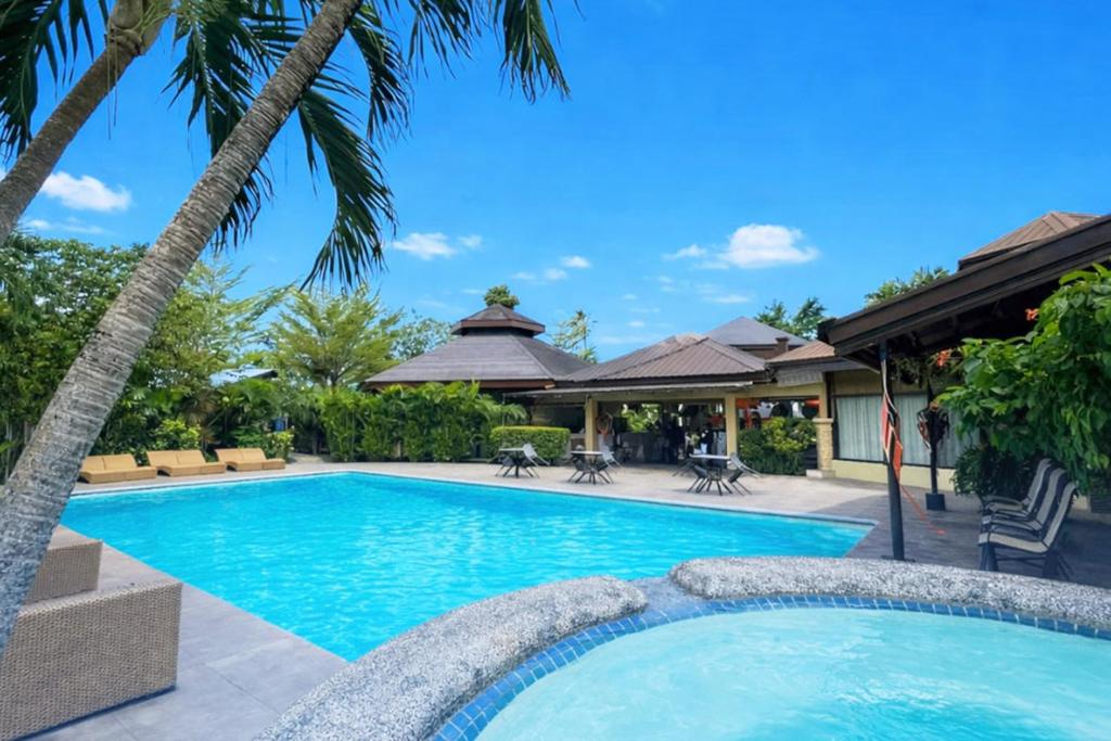 a swimming pool with palm trees and a house at Alta Cebu Resort Mactan powered by Cocotel in Mactan