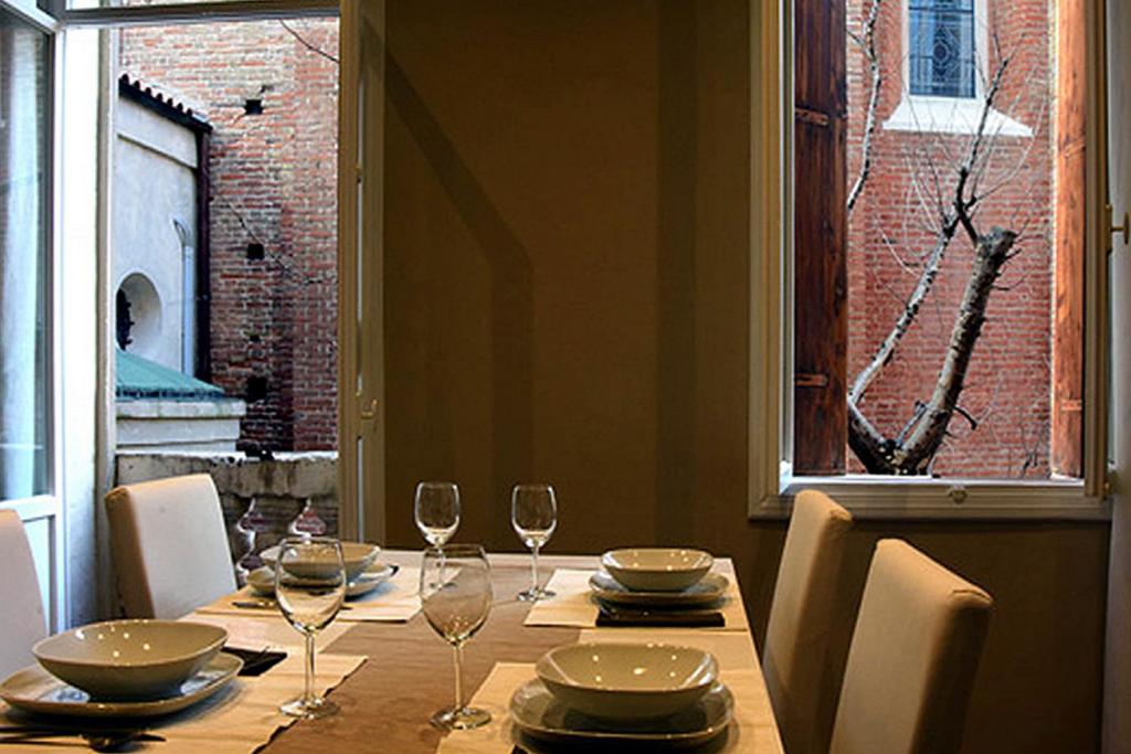 un tavolo da pranzo con bicchieri e piatti e una finestra di Studio in Casa Cogollo a Vicenza