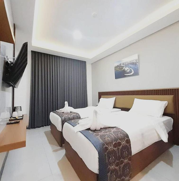 a hotel room with two beds and a television at Koa Living Semarang in Kalibanteng-kidul