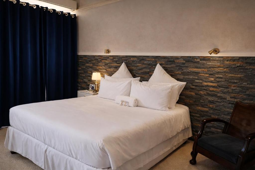 a bedroom with a large white bed and a chair at Concord Christian Guesthouse in Durban