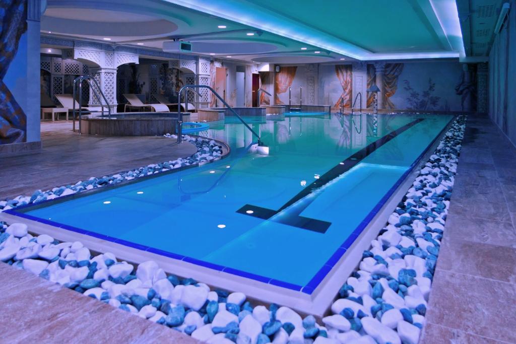 a swimming pool with blue water and rocks around it at Hotel St. Bruno in Giżycko