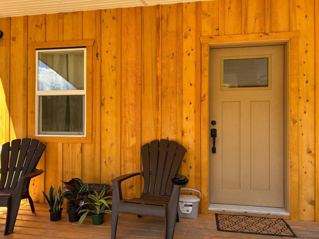 a wooden cabin with two chairs and a door at Mountains Edge Bungalow in Sayward