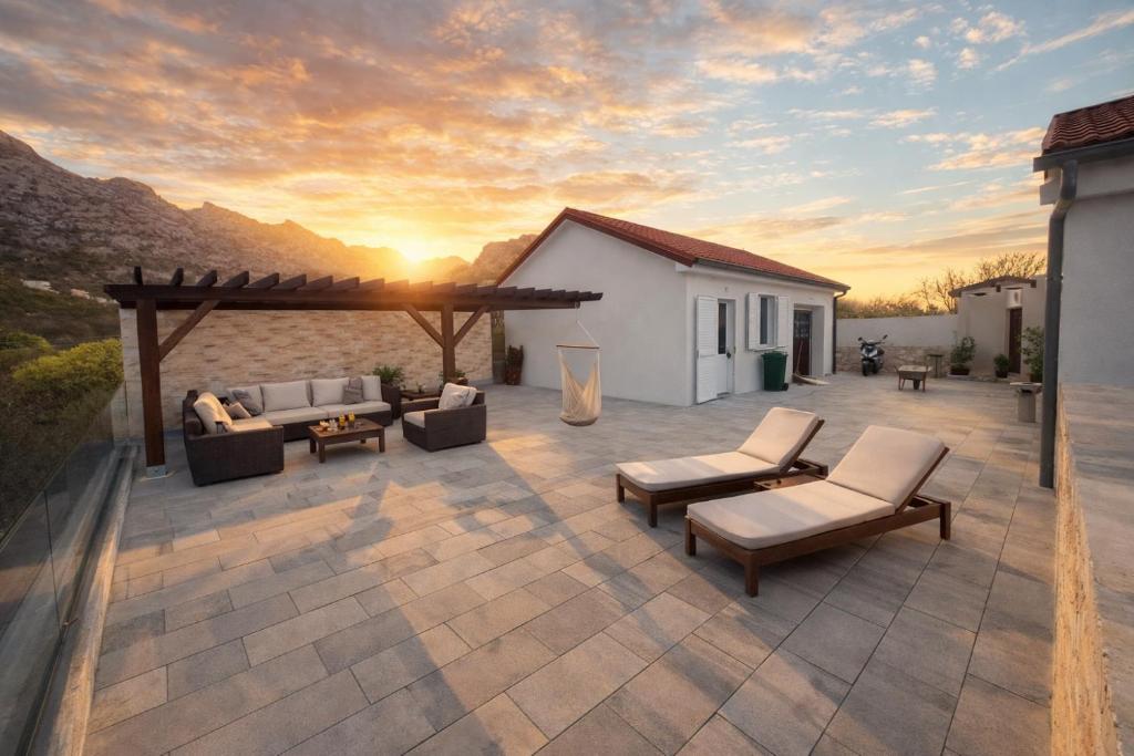a patio with couches and chairs and a sunset at Apartmani Mia in Karlobag