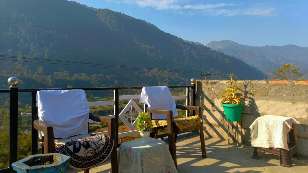 two chairs on a balcony with a view of a mountain at Dev Niwas in Nākuri