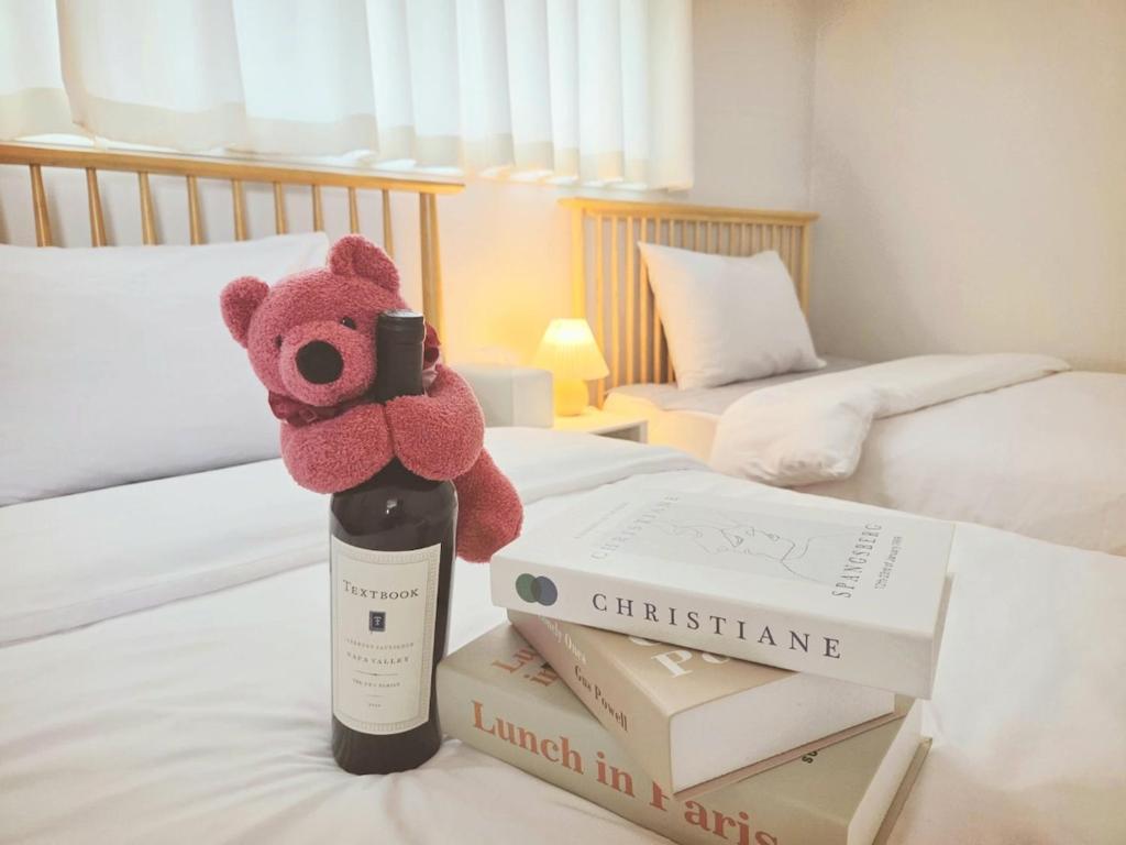 a stuffed teddy bear sitting on top of books on a bed at SlowNight, Suwon in Suwon
