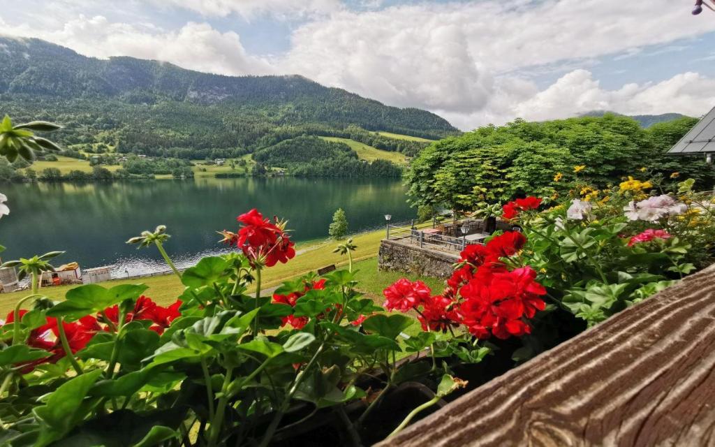 a view of a lake and flowers on a balcony at Pension Max Schraml in Grundlsee