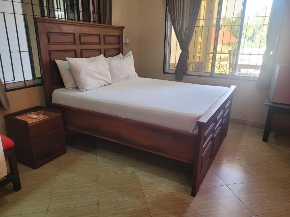 a large bed in a room with windows at KimyaKimya Pub & Lodge in Dar es Salaam