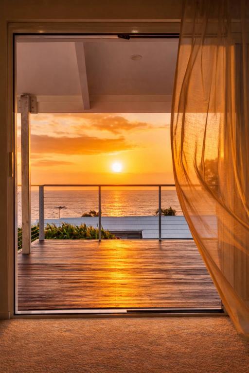 a window view of a sunset from a house at Oceanview Sunset Villa Hallett Cove 3BR 2Bath Large Deck Free Parking in Halletts Cove