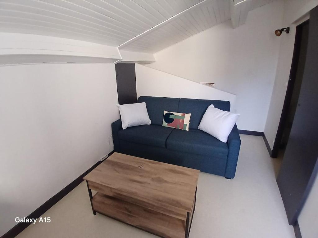 a living room with a blue couch and a wooden coffee table at studio coralie in Saint-Flour